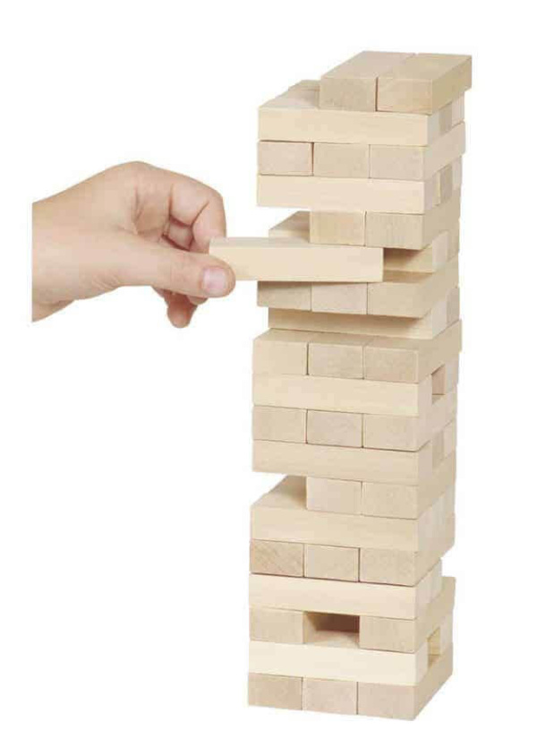 Hand greift nach Holzbaustein, um Turm im Gleichgewicht zu halten – hochwertiges Spielzeug für Kinder.